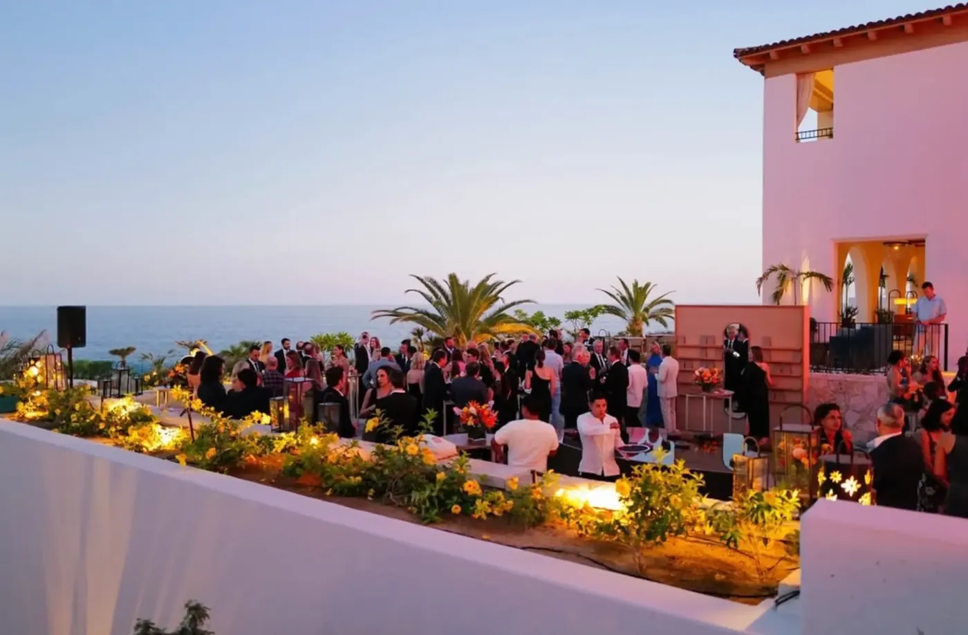 Oceanfront wedding cocktail hour at sunset with guests and lanterns