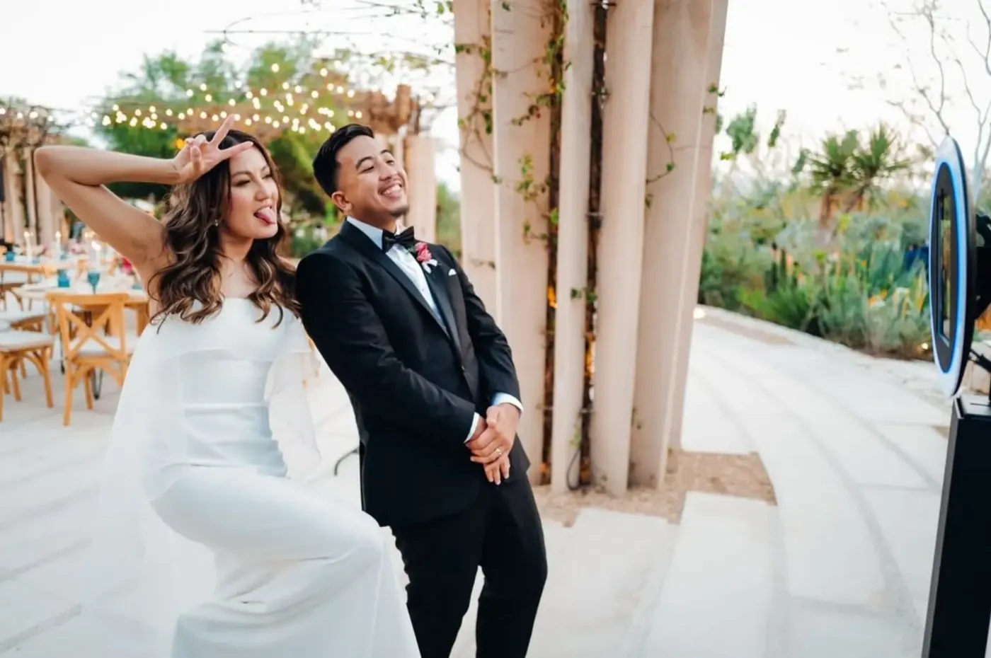Bride and groom posing at a ring light photo booth during an outdoor wedding reception