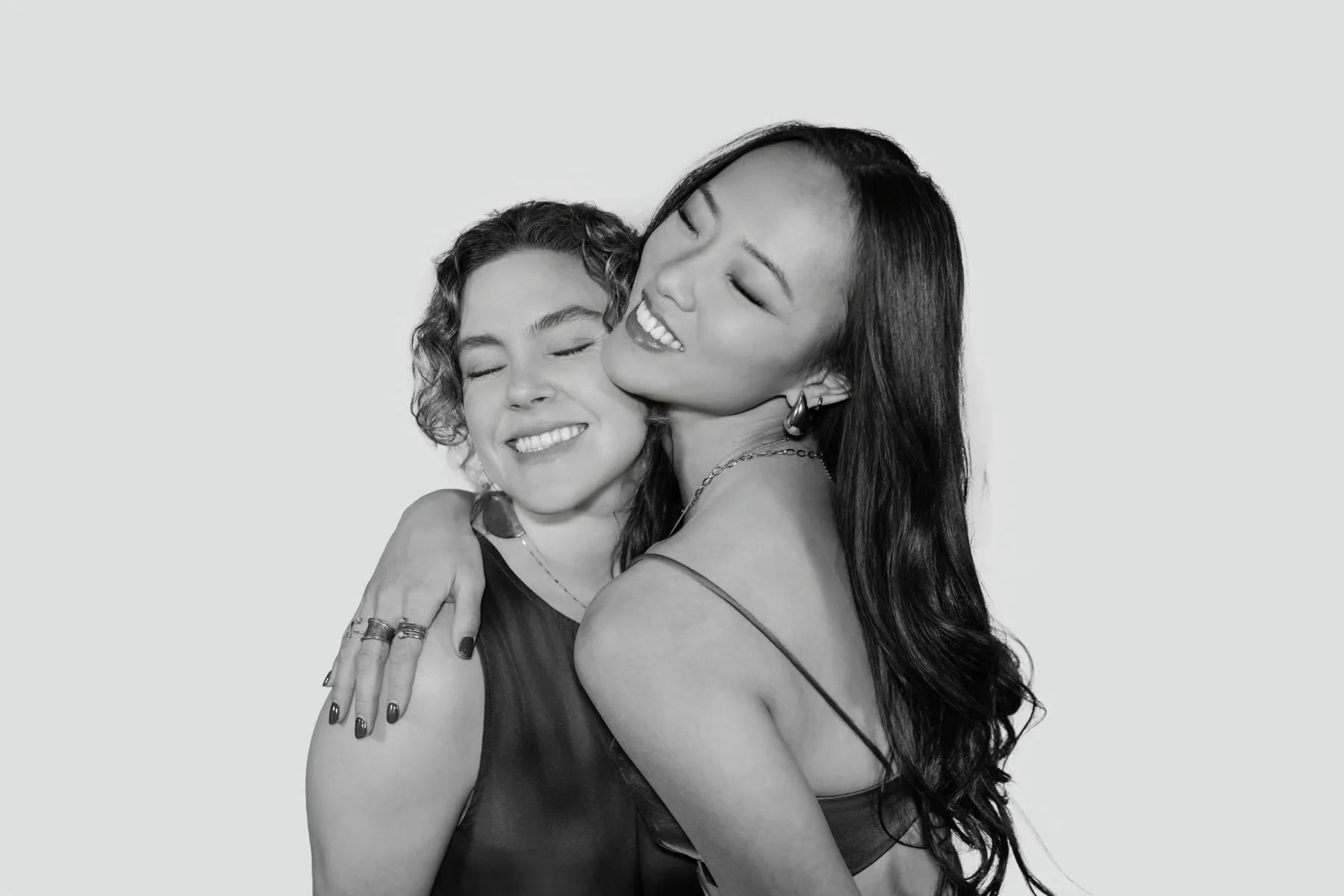 Two friends hugging and smiling in the Glam Booth — black and white portrait
