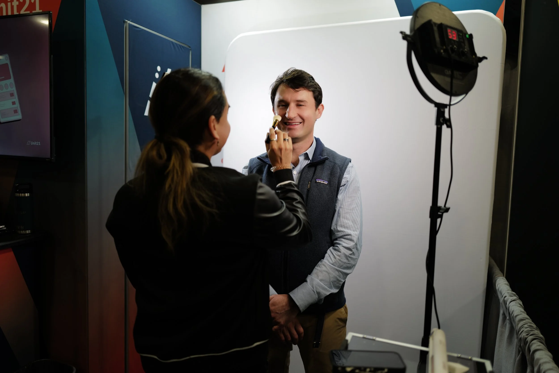 Glam stylist applying makeup to a guest before their headshot