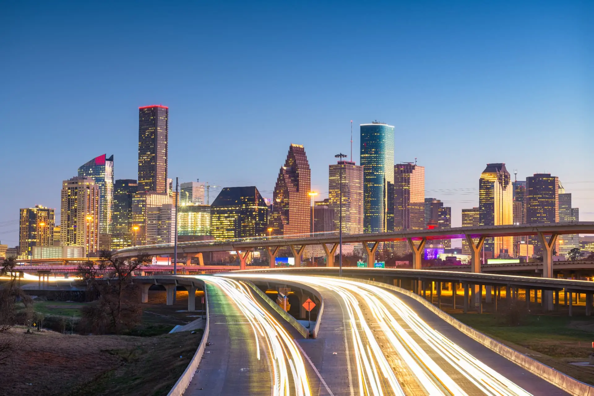 Downtown Houston skyline at dusk above lit freeway light trails